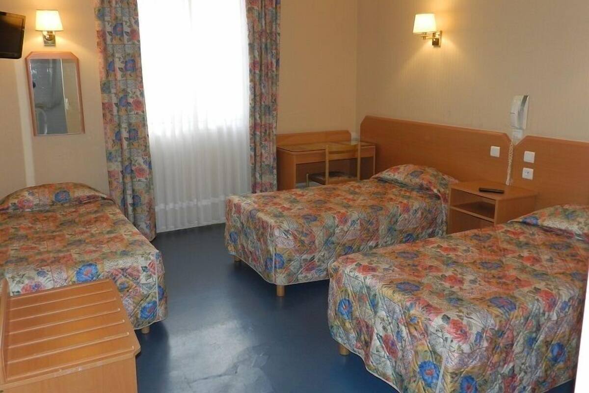 Een hotelkamer met twee enkele bedden, een bureau, een stoel, een spiegel en twee wandlampen.