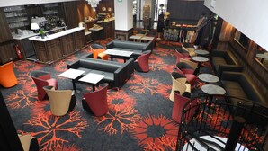A modern lounge area with seating arrangements, a bar, and a staircase. - Hotel Gloria et Avenue (Lourdes)