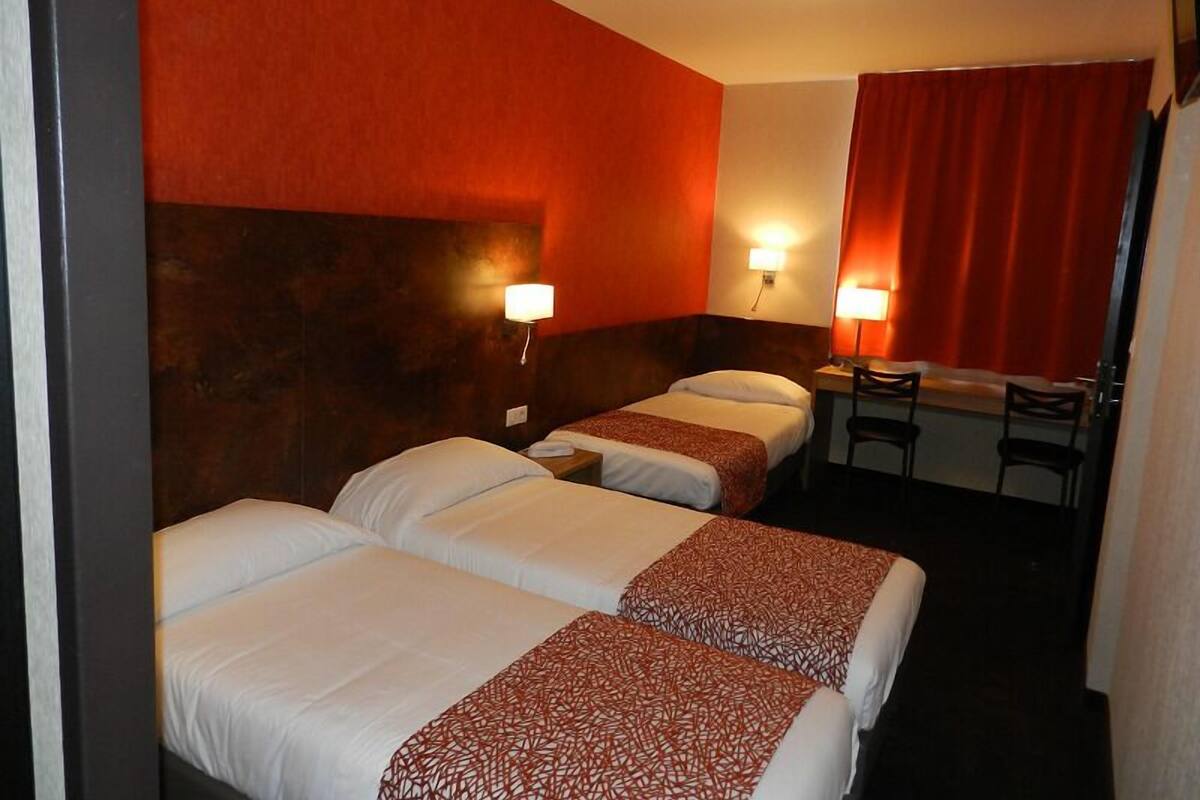 Een hotelkamer met twee bedden, een bureau en een stoel.