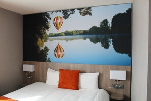 A hotel room with a large wall mural of a lake and hot air balloons, a bed with white and orange bedding, and bedside lamps. - The Originals City, Hôtel La Terrasse, Tours Nord (Tours)