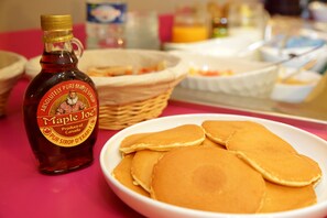 A bottle of Maple Joe syrup, pancakes, and a basket of food items on a table. - The Originals City, Hôtel La Terrasse, Tours Nord (Tours)