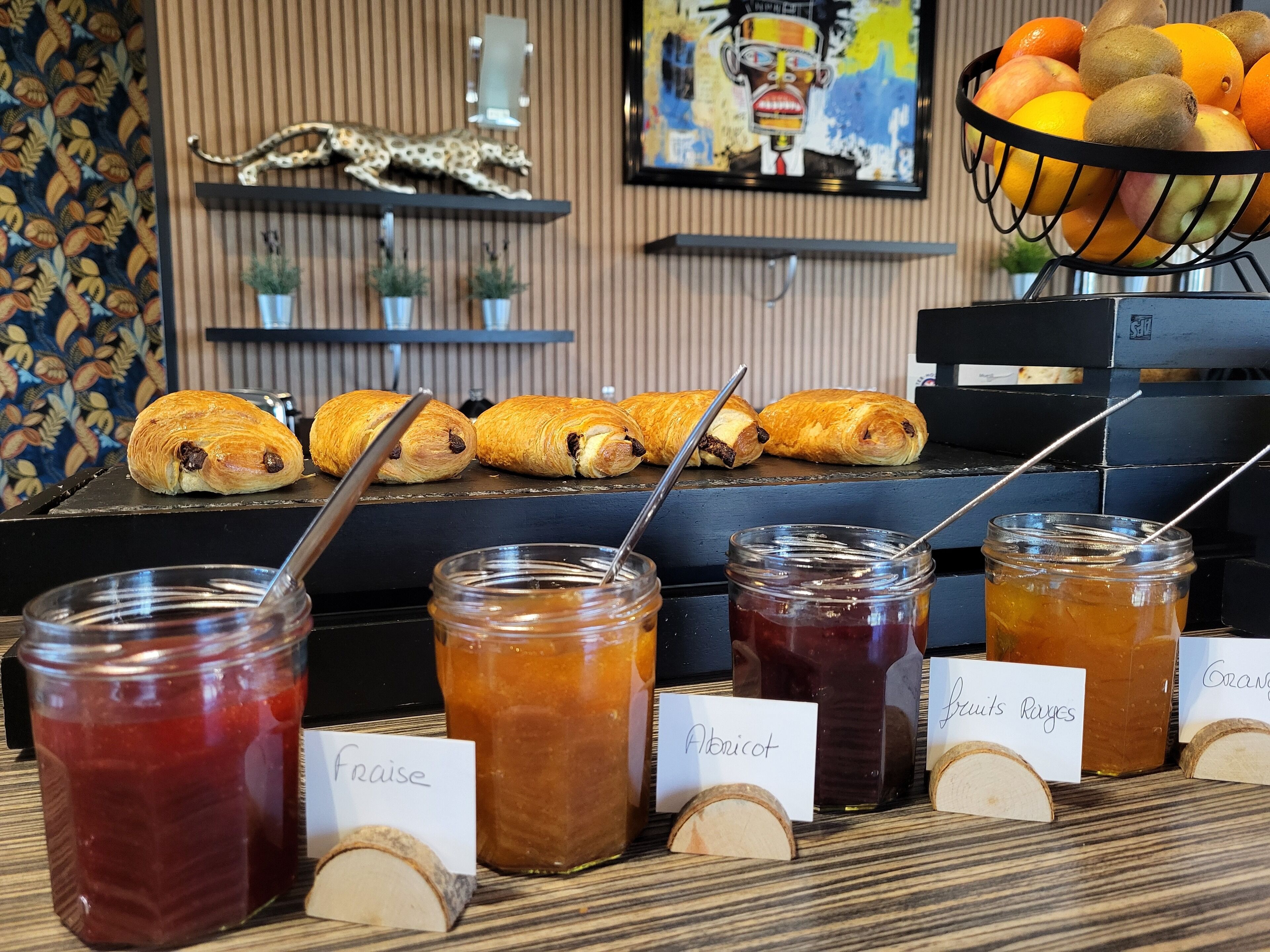 A breakfast buffet with pastries, jams, and a fruit basket.