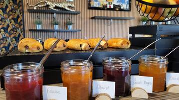 A breakfast buffet with pastries, jams, and a fruit basket.