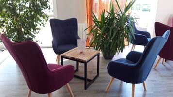Een moderne zithoek met een houten tafel, twee blauwe stoelen en een rode stoel.