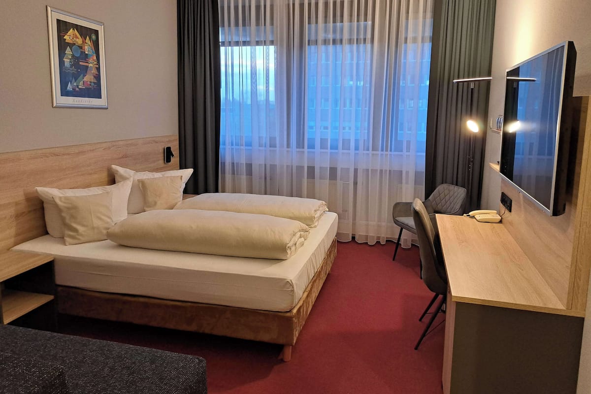 Relax in a stylish room with a large bed, desk, and flat-screen TV, offering a city view.