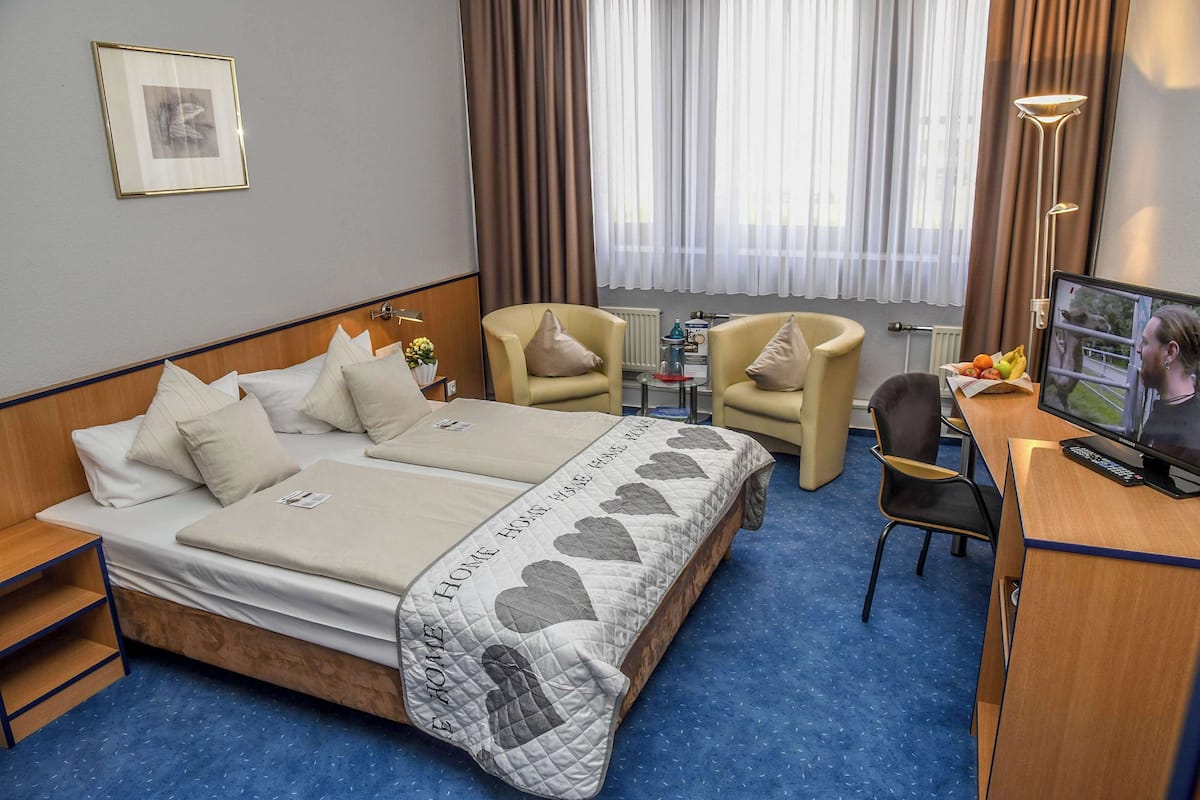 Relax in this inviting room with a comfortable bed, two chairs, and a TV.