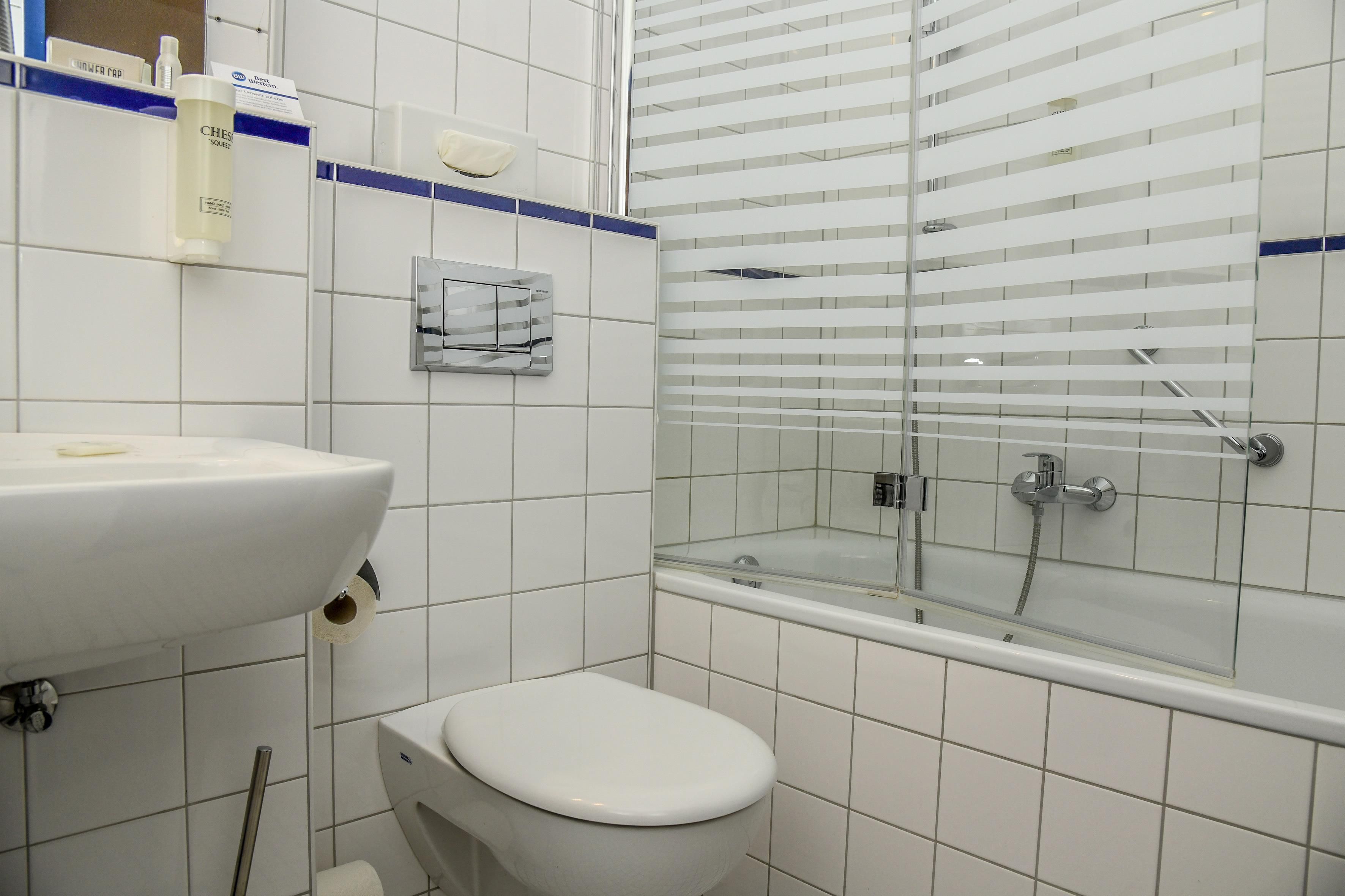 A bathroom with a white sink, toilet, and glass-enclosed shower area.