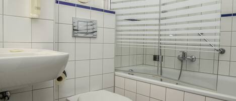 A bathroom with a white sink, toilet, and glass-enclosed shower area.