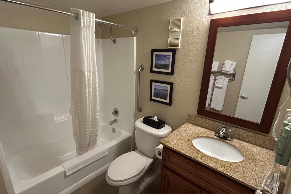 A bathroom with a bathtub, toilet, sink, and a mirror.