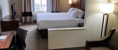 Een hotelkamer met een bed, bureau, stoel, bank en lamp.