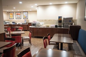 Un restaurant avec des banquettes et des tables, un distributeur de café et un comptoir où sont exposés des produits alimentaires.