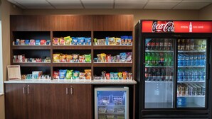 Un bar proposant divers aliments emballés et un réfrigérateur rempli de Coca-Cola.