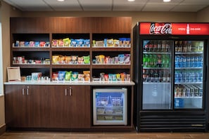 Un bar de aperitivos con diversos productos envasados y un refrigerador de Coca-Cola.