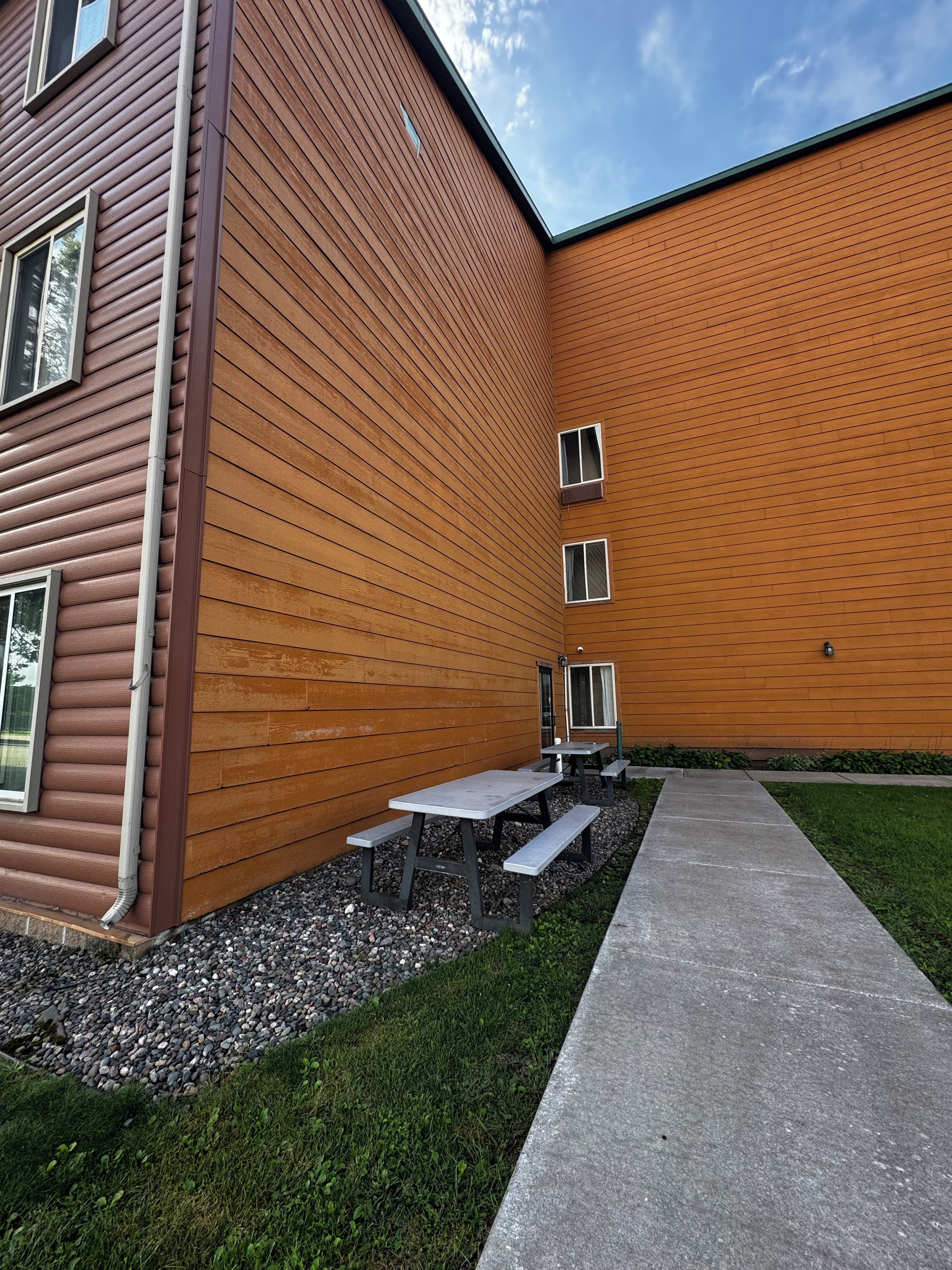 A building with a sloped roof, a gravel pathway, and outdoor seating.
