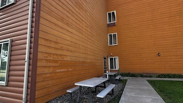 Un edificio con techo inclinado, un camino de grava y mobiliario exterior.