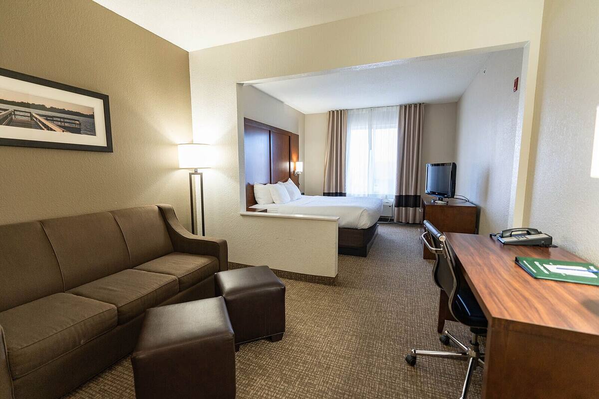 A hotel room with a sofa, a bed, a desk, and a TV.