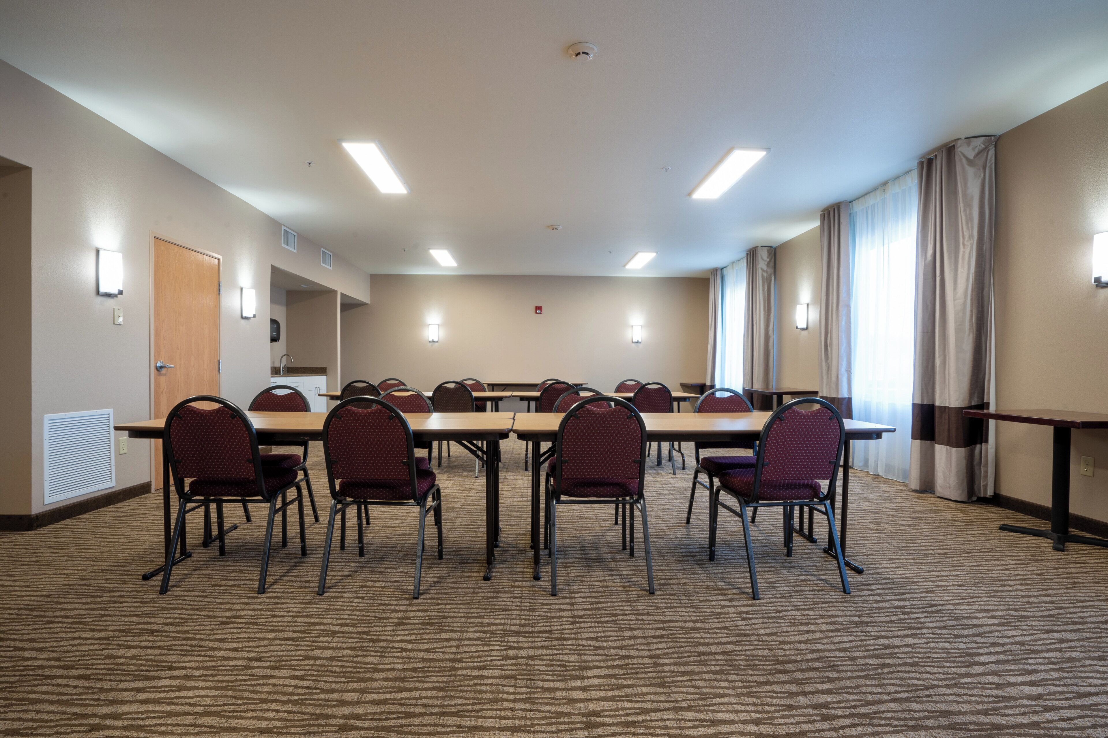 Een vergaderruimte met een lange tafel, meerdere stoelen en verlichting van bovenaf.