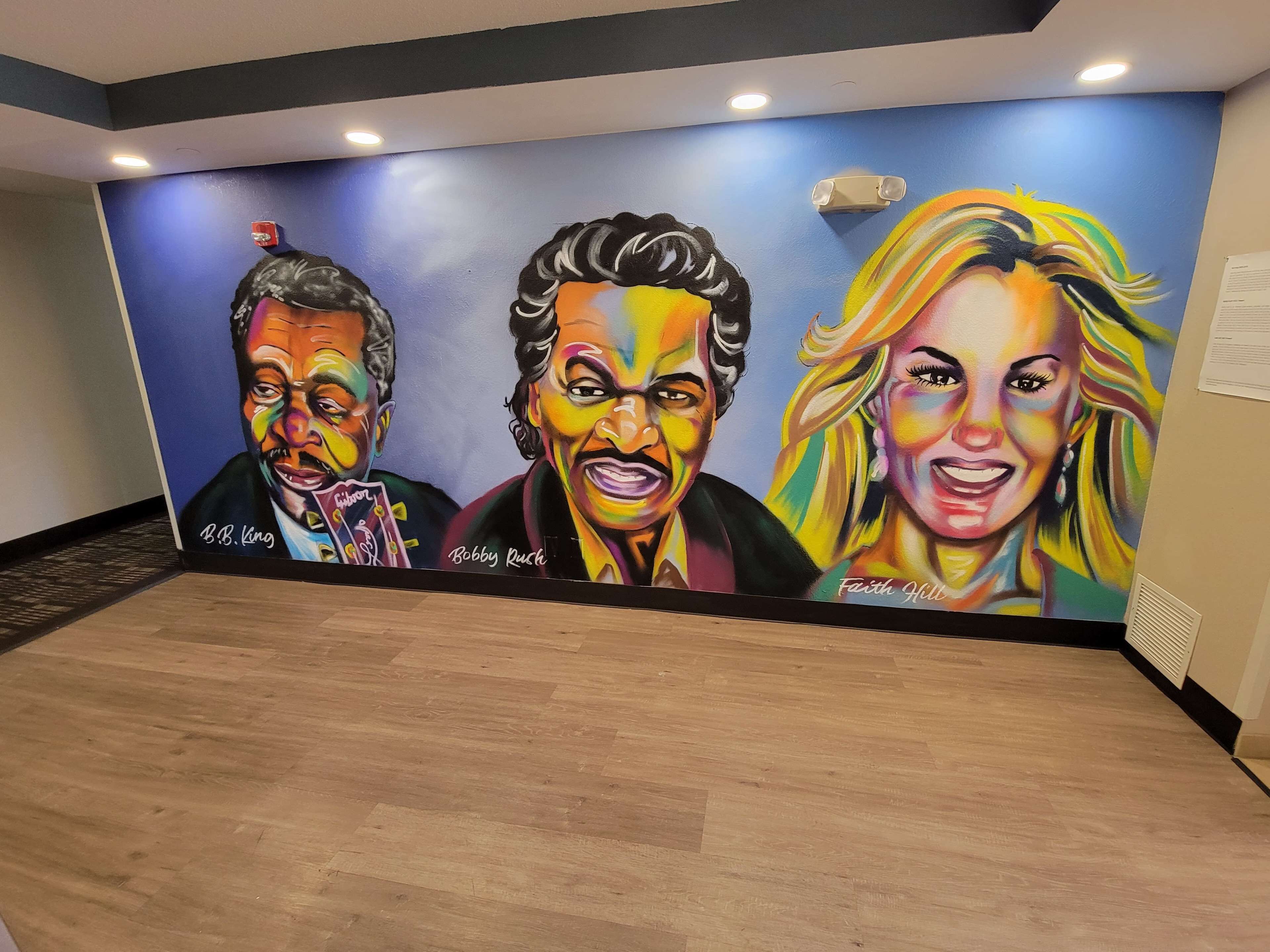 A mural with three figures, each signed by an artist.
