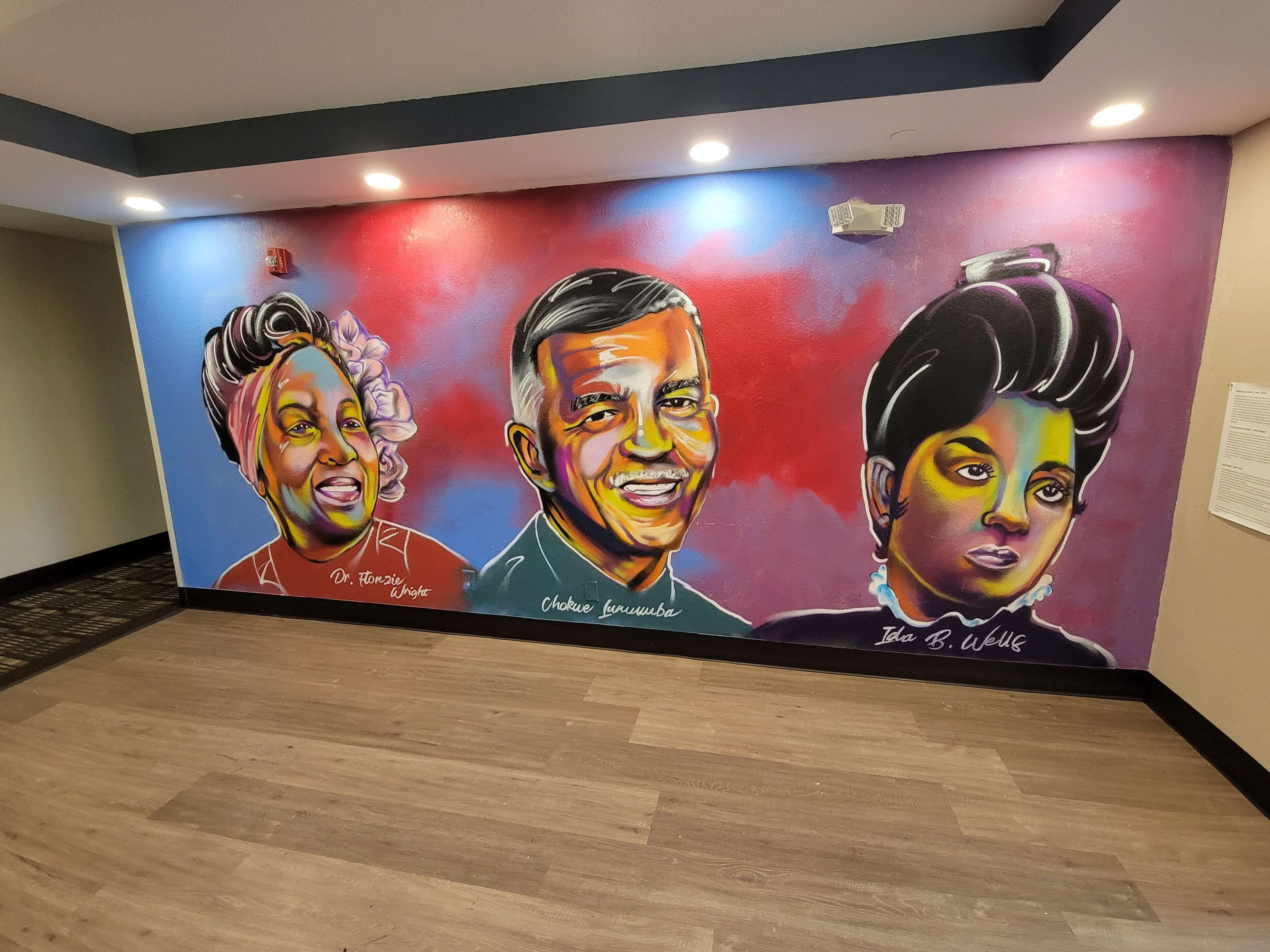 A mural with portraits of individuals in a hallway.