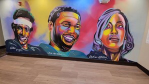 A vibrant mural with three portraits of individuals, each signed by the artist.