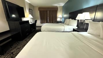 A hotel room with two beds, a desk, a chair, a TV, and lamps.
