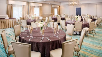 A banquet hall with round tables set for events, equipped with chairs and table settings.