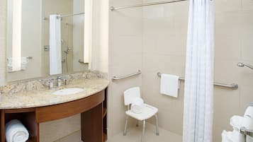 Une salle de bain moderne avec un lavabo en marbre, une cabine de douche en verre, une chaise blanche et un porte-serviettes.