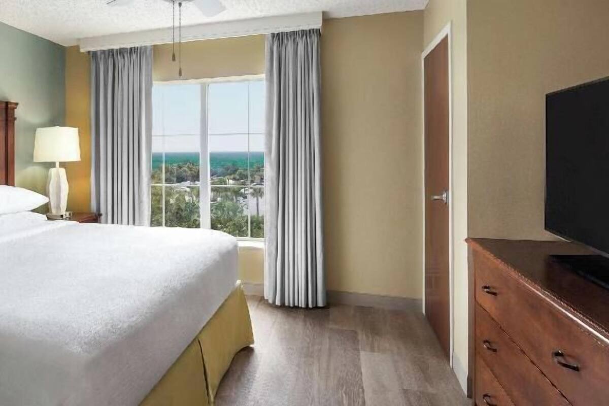 Une chambre d’hôtel avec un grand lit, une télévision, une fenêtre avec des rideaux et une vue sur la ville.