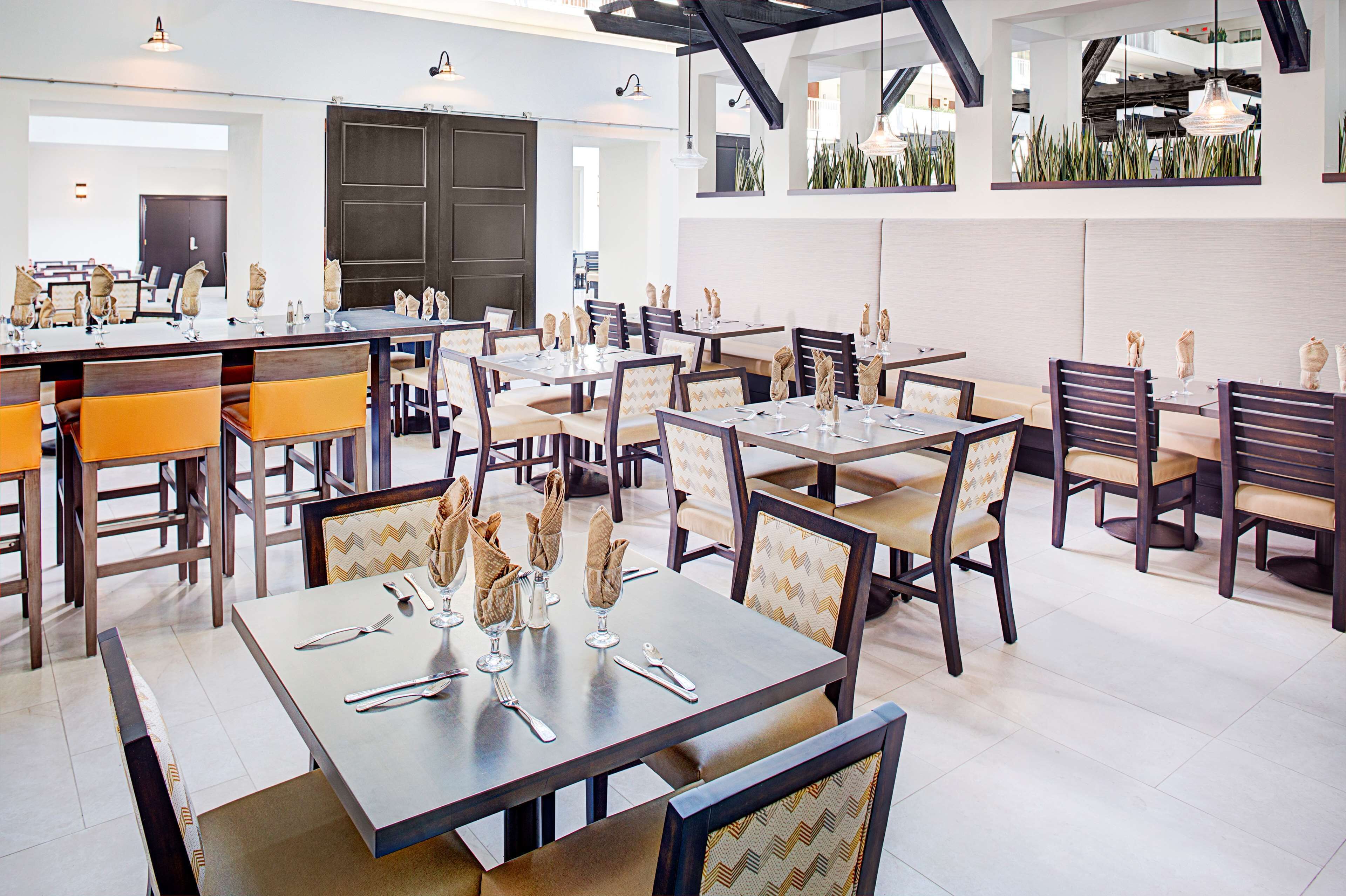 Un restaurante moderno con varias mesas y sillas, que presenta un diseño limpio y contemporáneo.