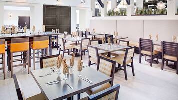 A modern restaurant with multiple dining tables and chairs, featuring a clean and contemporary design.