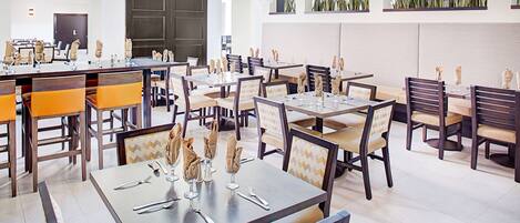 Un restaurante moderno con varias mesas y sillas, que presenta un diseño limpio y contemporáneo.