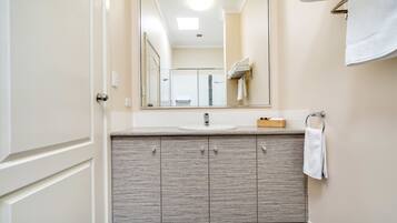 A bathroom with a large mirror, a sink, and a towel rack.