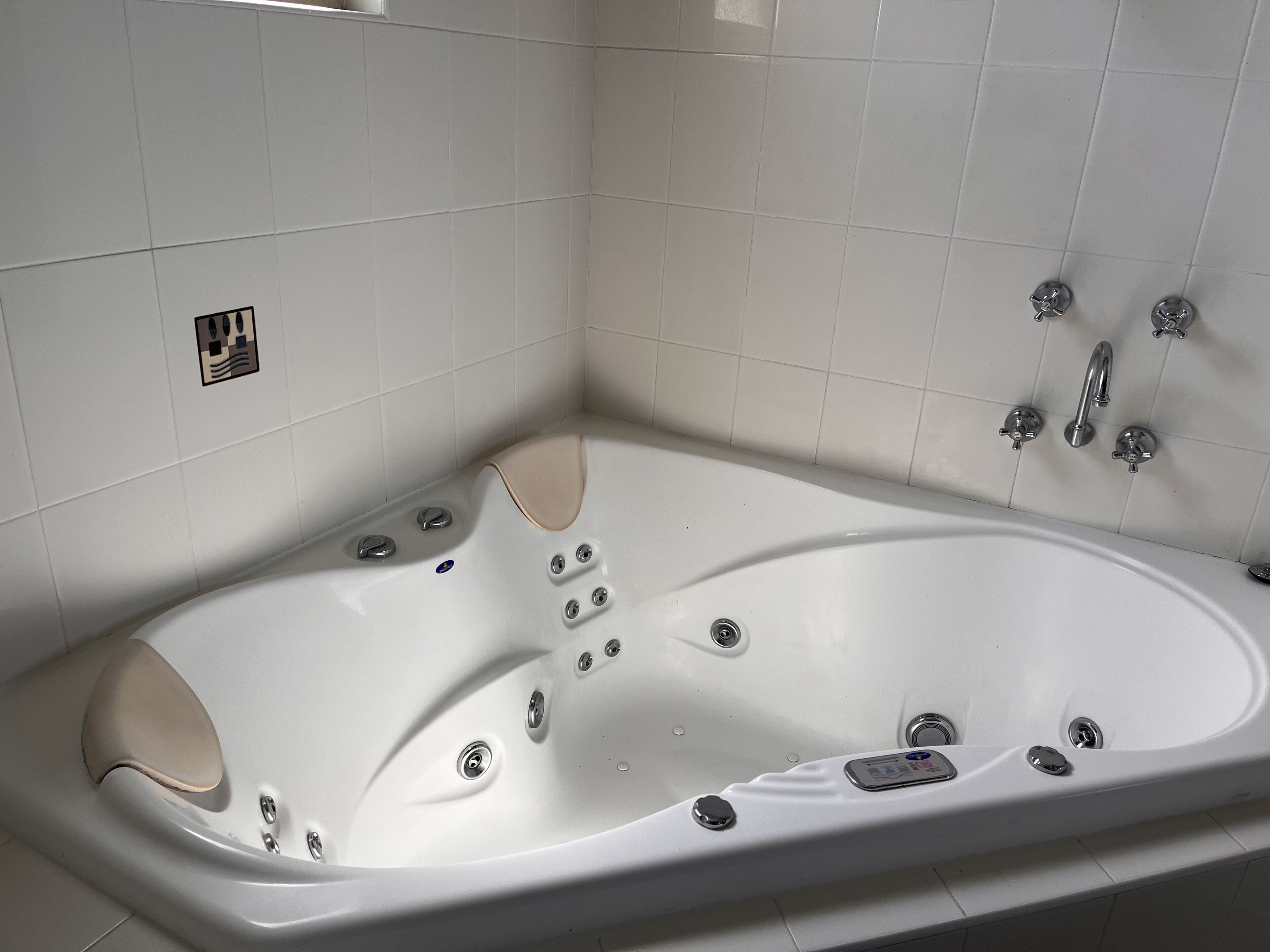 A modern bathroom with a large freestanding bathtub, a showerhead, and a control panel.