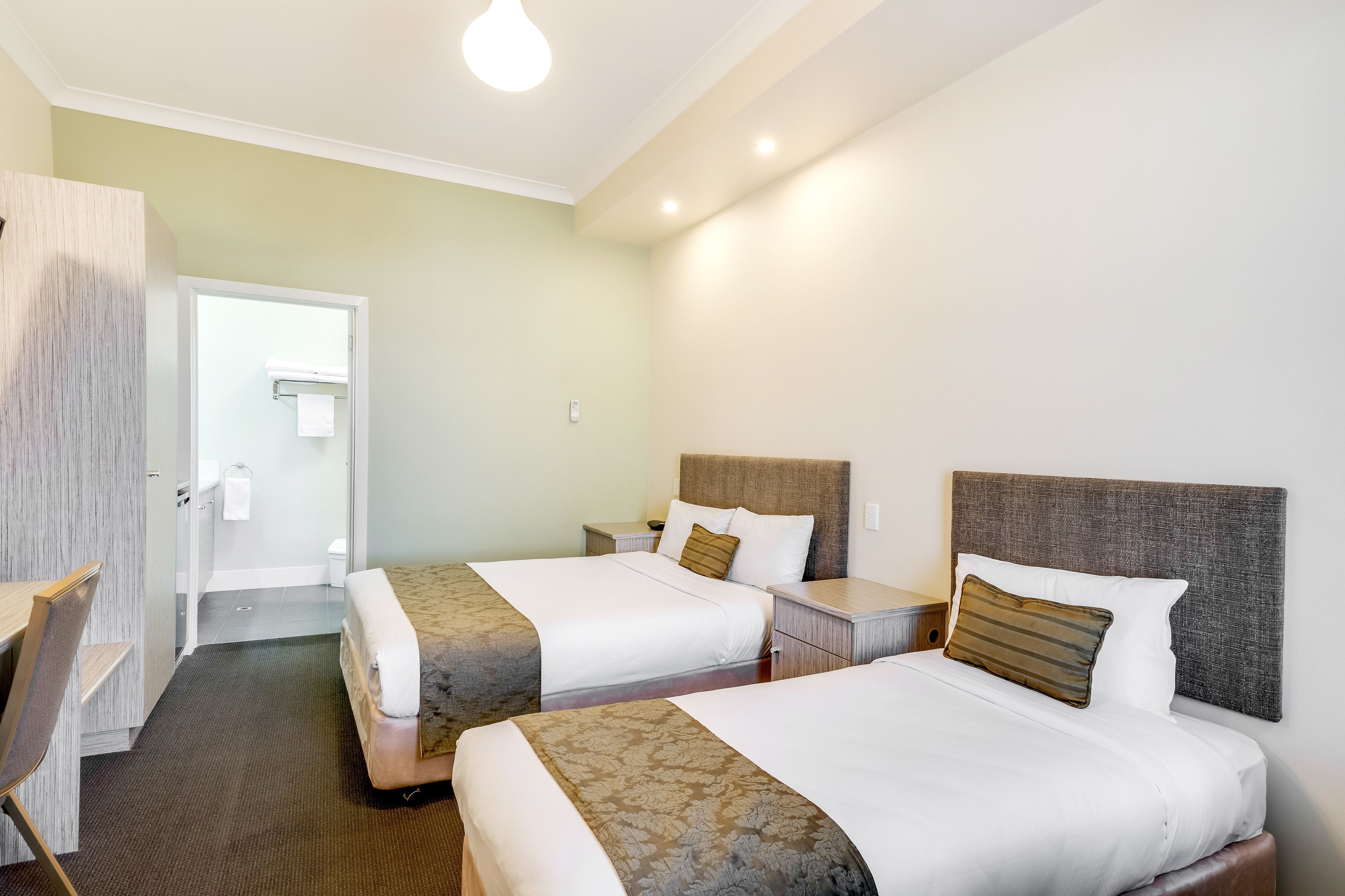 Une chambre d’hôtel avec deux lits, un bureau et une chaise.