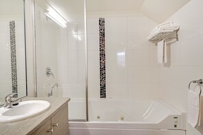 Un bagno moderno con doccia a vetro, una vasca da bagno bianca e un mobile lavabo con specchio.