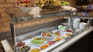Un buffet proposant une variété de fruits et de légumes, notamment des pommes, des bananes, des raisins et du melon.