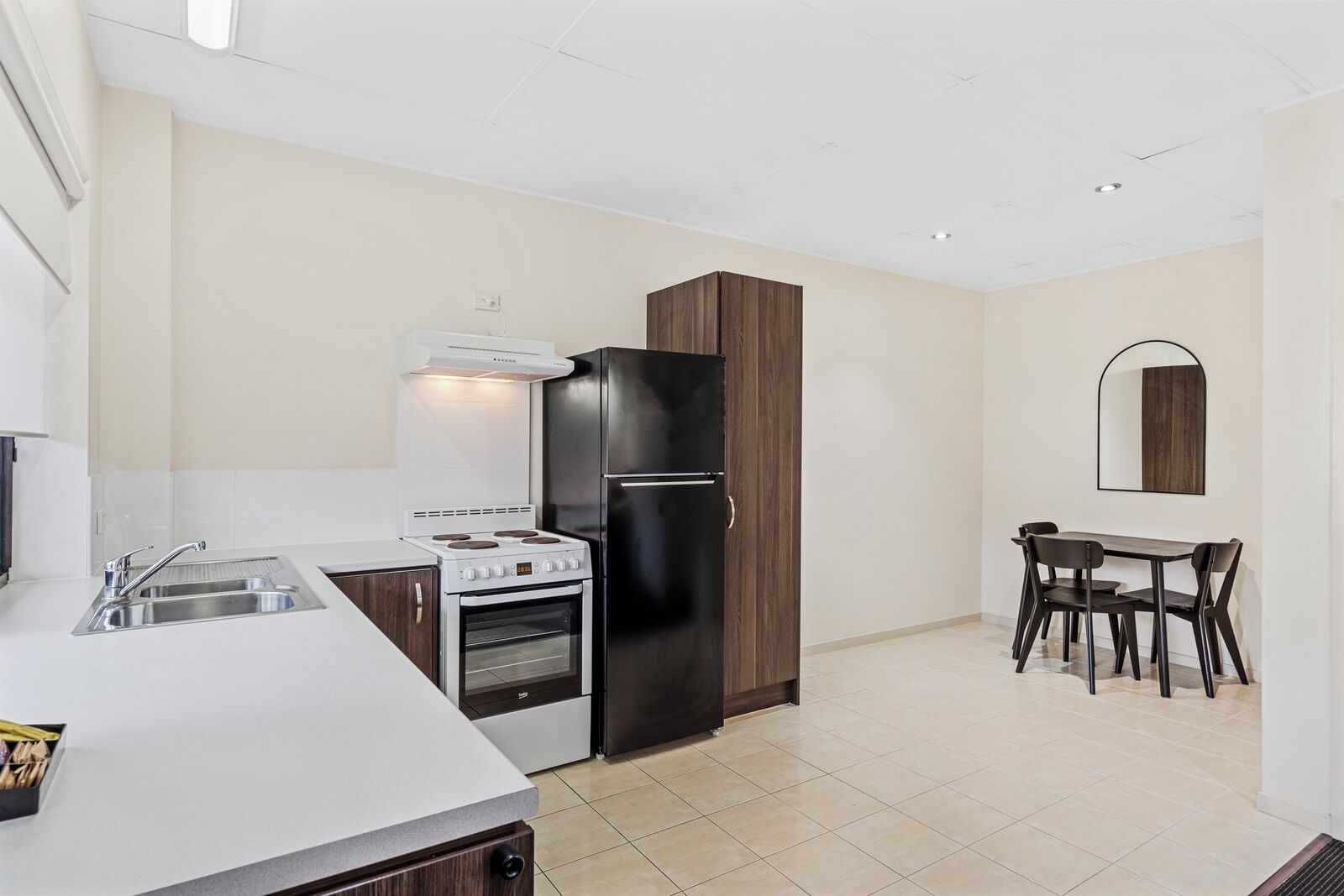 Cocina moderna con estufa, horno y refrigerador negro. Hay un comedor con mesa y sillas.
