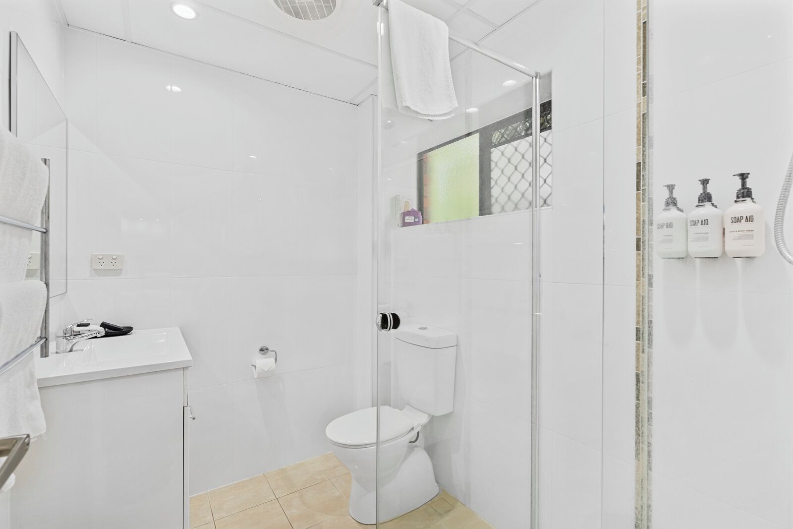 A modern bathroom with a glass shower enclosure, a white toilet, and a sink with a mirror.