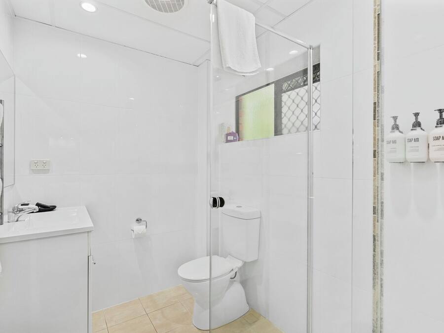 A modern bathroom with a glass shower enclosure, a white toilet, and a sink with a mirror.
