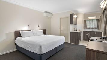 A hotel room with a bed, a desk, a kitchenette, and a bathroom.