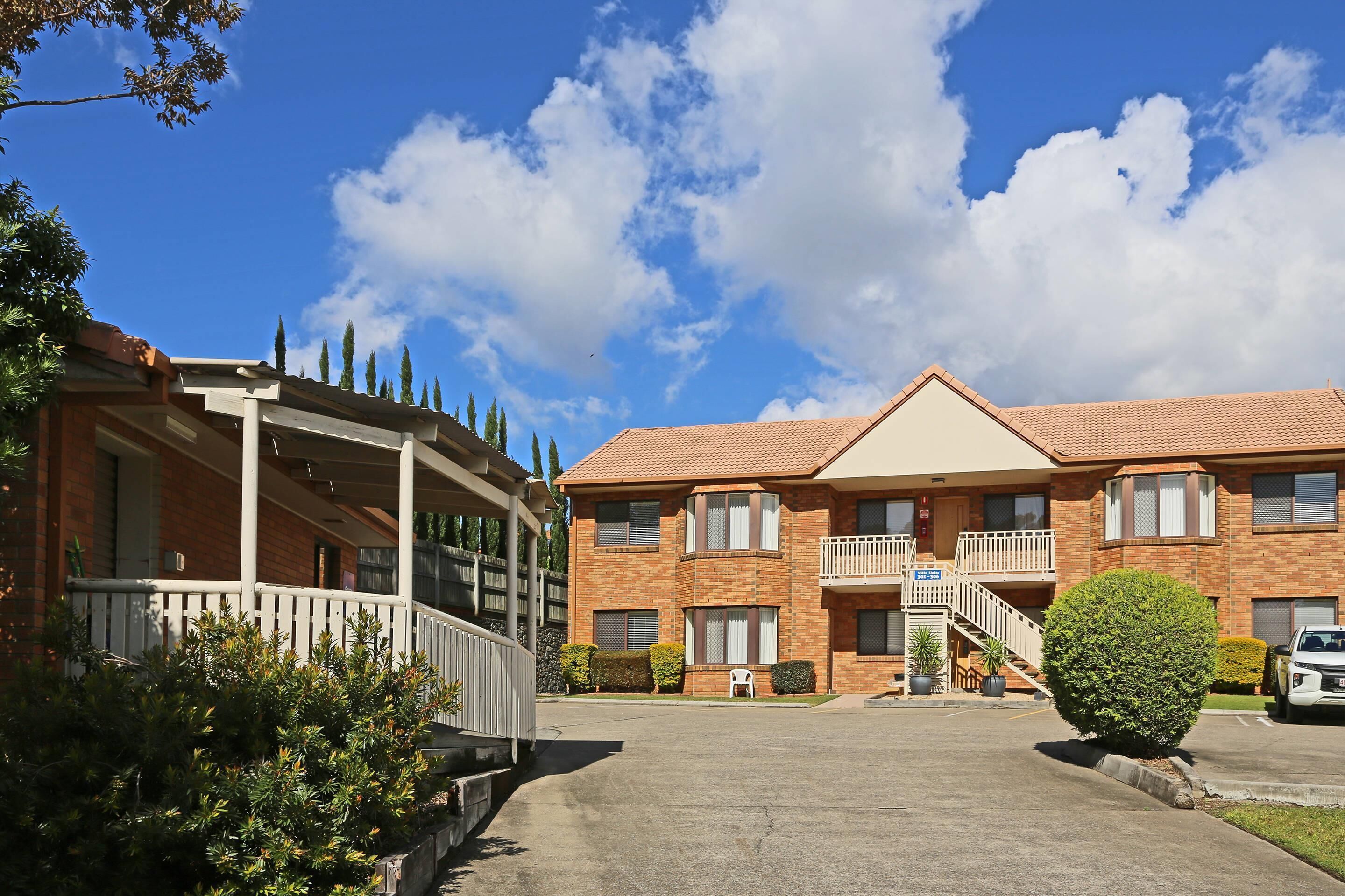 A two-story brick building with a covered porch and a balcony.