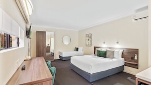 Une chambre d’hôtel équipée d’un lit, d’un bureau, d’une chaise, d’un miroir et d’un téléviseur fixé au mur.