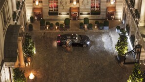 Un amplio patio de hotel con zona pavimentada, columnas y un coche estacionado en el centro.
