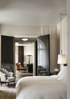 A hotel room with a large bed, a seating area with a sofa and armchairs, and a separate dining area. - Rosewood London (London)