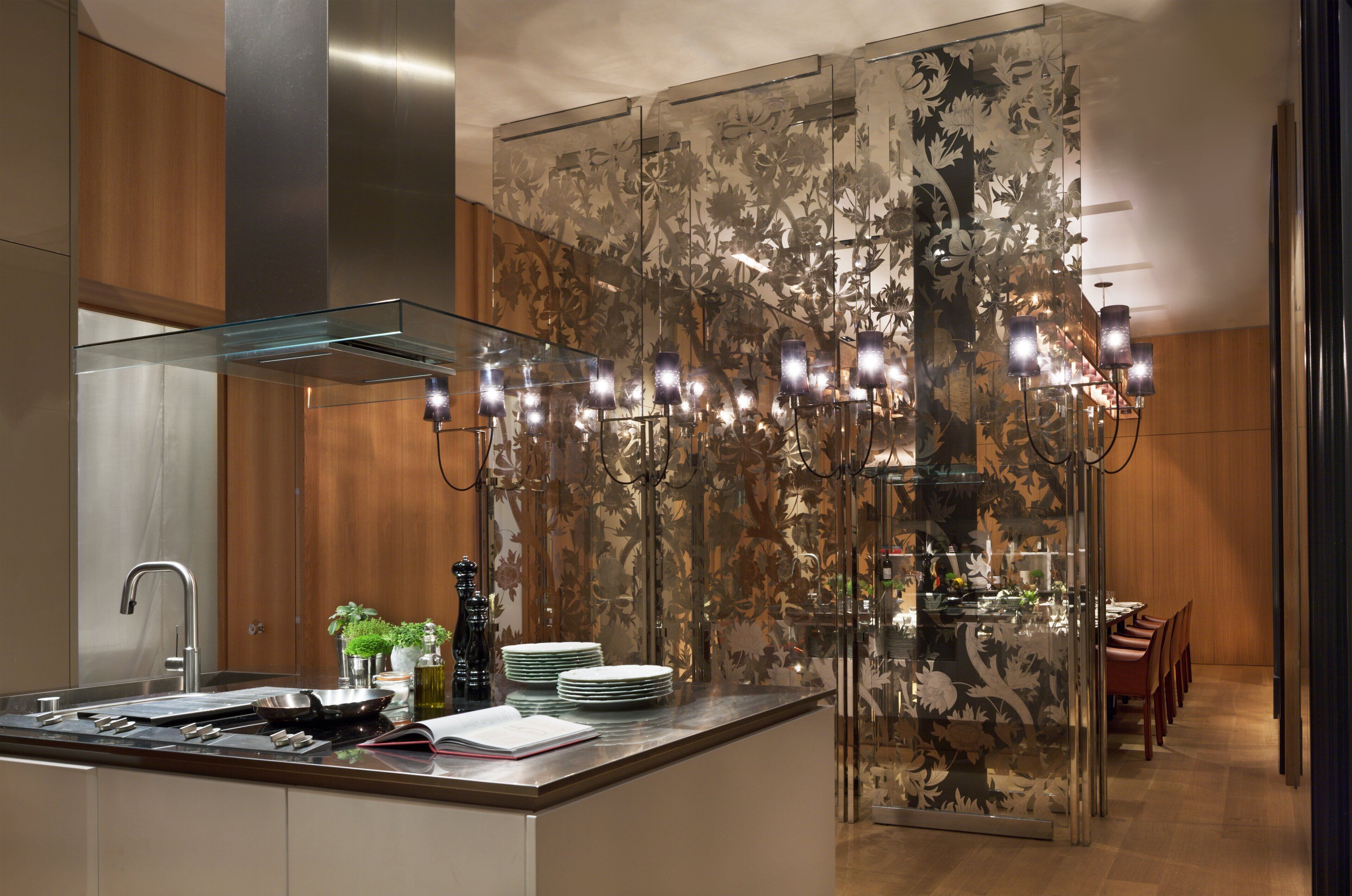 A modern kitchen with a glass island, stainless steel appliances, and a decorative floral wall panel.