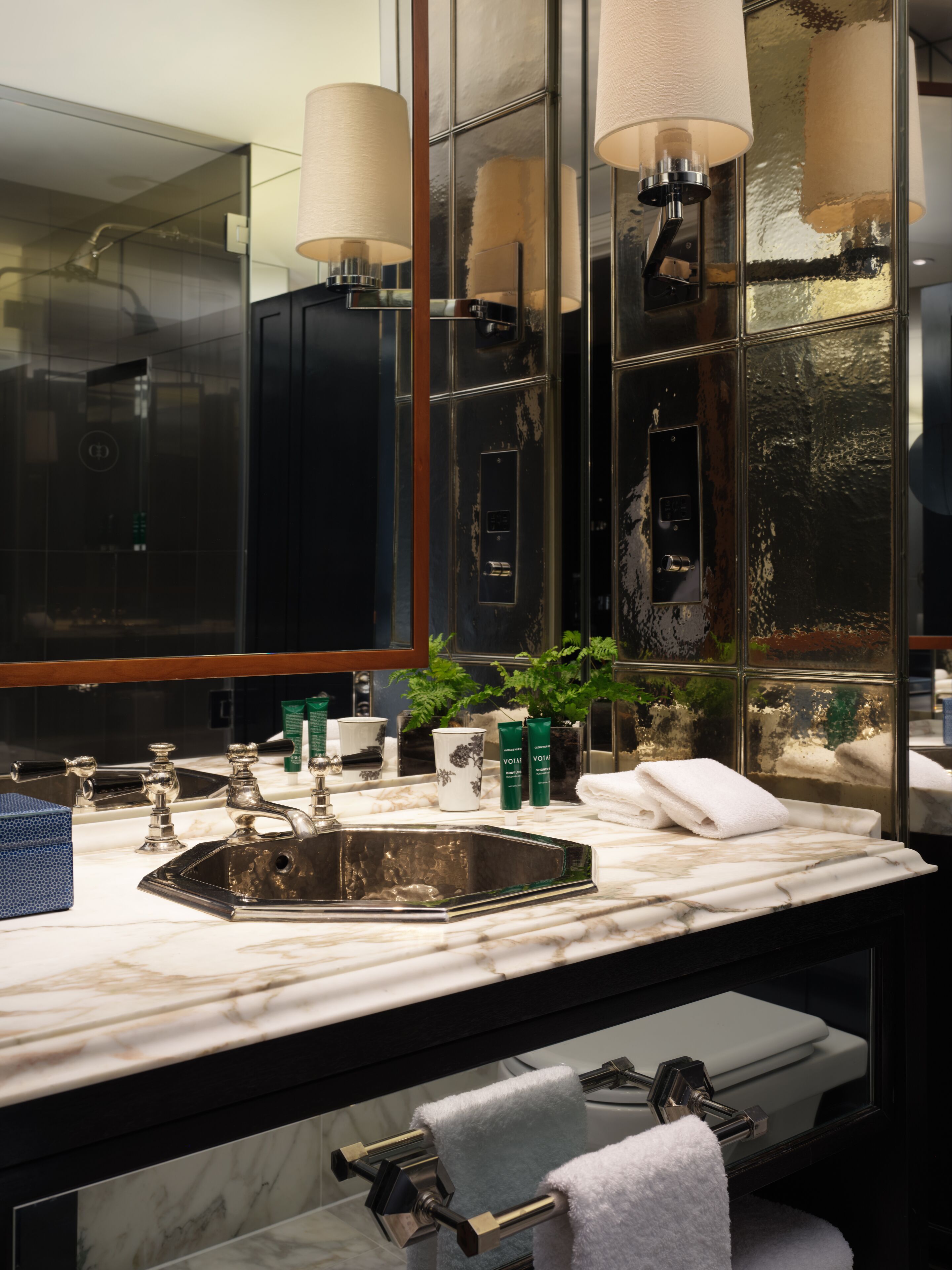 A modern bathroom with a large mirror, a marble sink, and two towel racks.