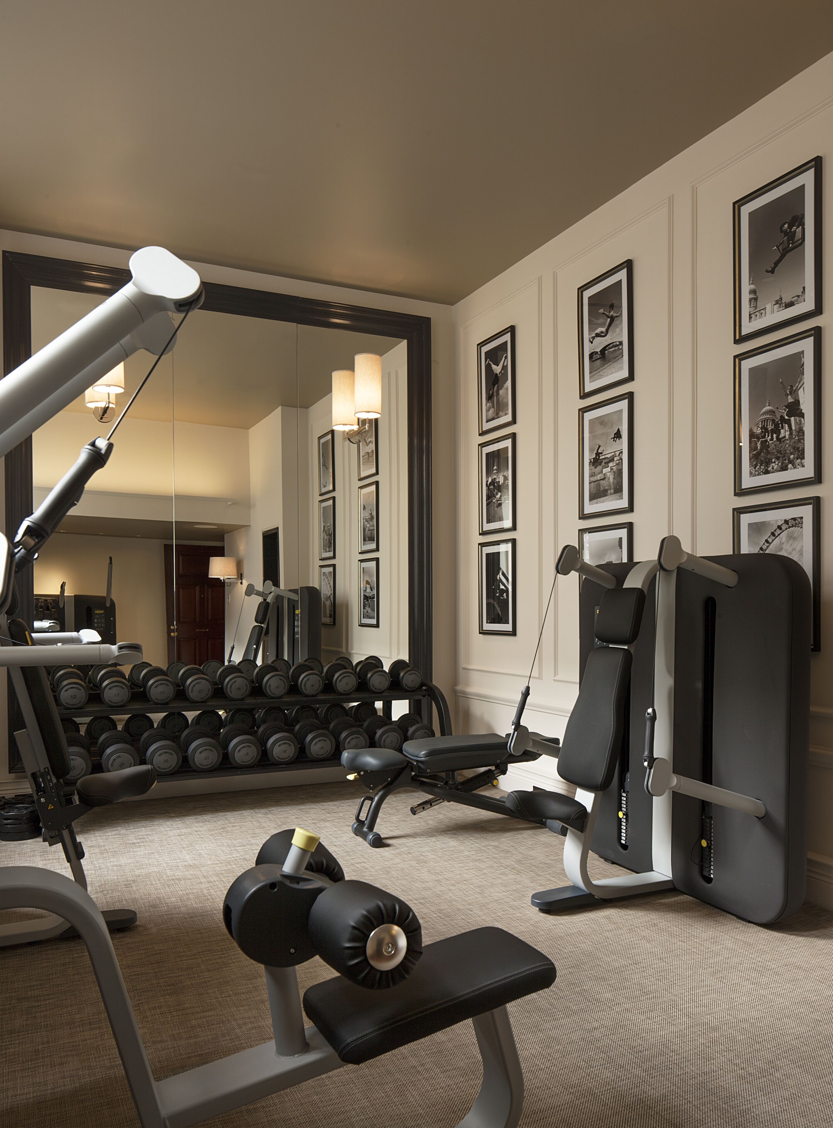 A gym with exercise equipment, a mirror, and a wall with framed pictures.