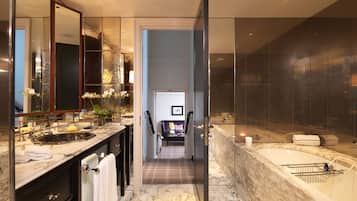Un baño moderno con lavamanos de mármol, un espejo grande y una zona de ducha separada.