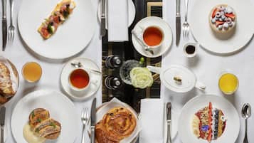 Une table mise pour le petit-déjeuner, avec différents plats, des tasses de thé et une théière.