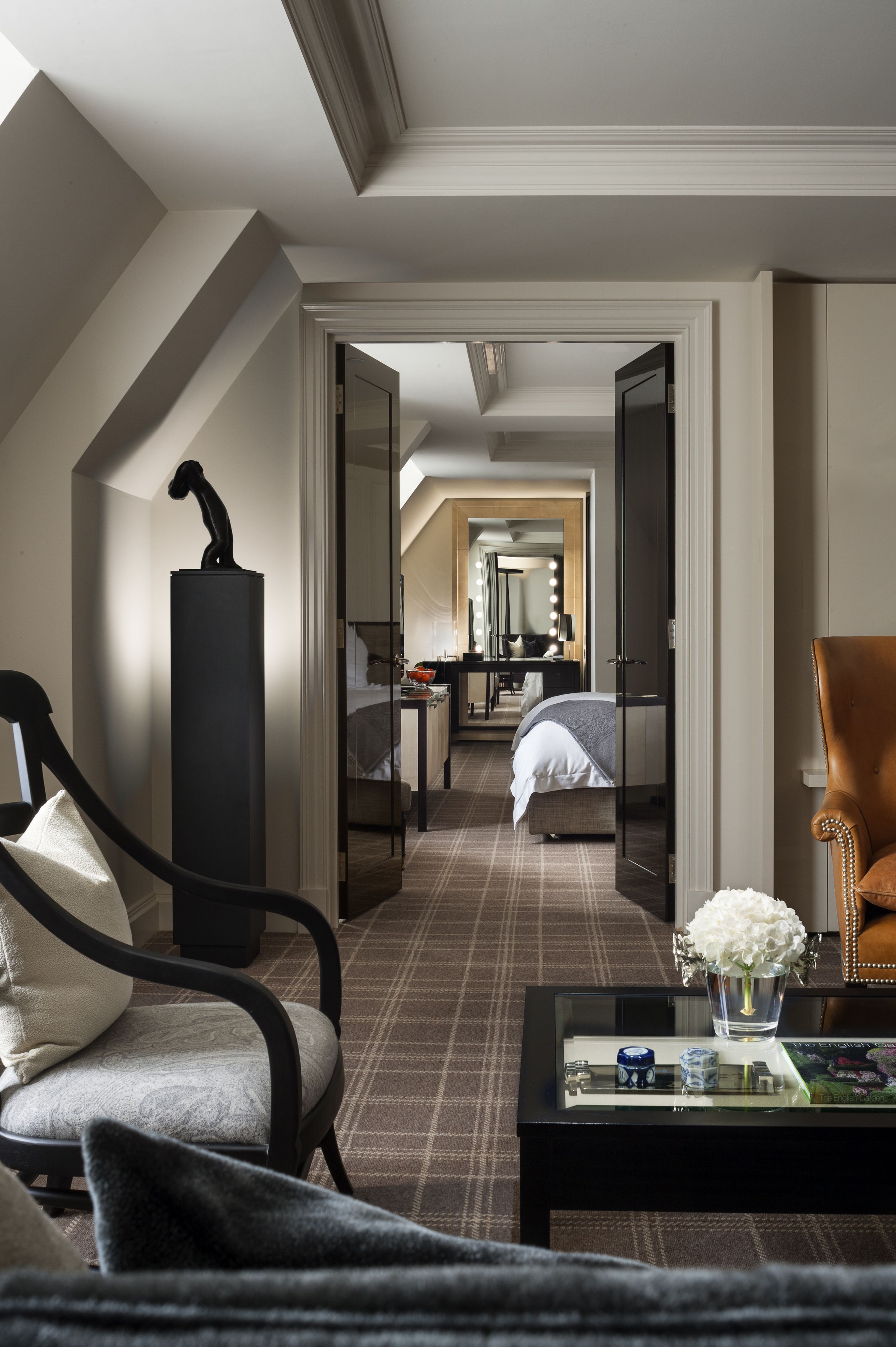 Ein Hotelzimmer mit modernem Design, ausgestattet mit einem großen Bett, einer Sitzecke mit Stuhl und Tisch sowie einem Spiegel im Hintergrund.